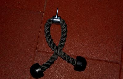 High angle view of metal hanging on rope against red background