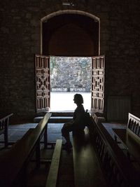 Side view of woman sitting on bench in church