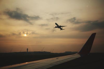 Airplanes flying against sky at sunset