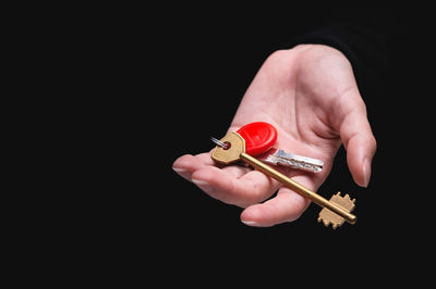 Cropped hand of person holding figurine against black background