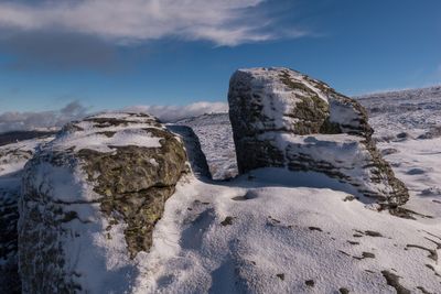 Rock formation by sea against sky during winter