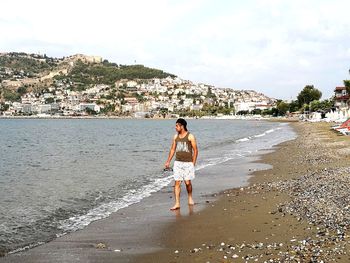 Rear view of man standing on beach against sky