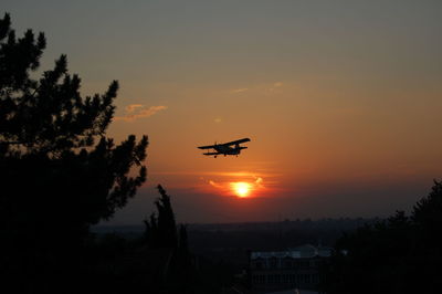 Low angle view of silhouette airplane against sky during sunset