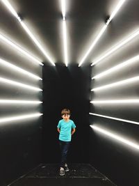 Full length of boy standing in illuminated corridor