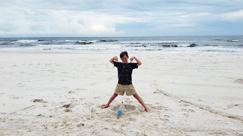 Portrait of boy standing on beach against sky