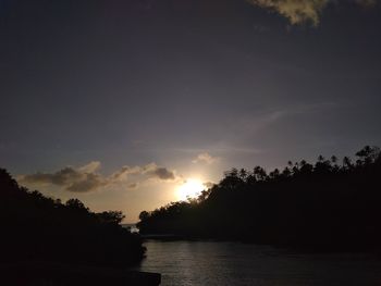 Silhouette trees by lake against sky during sunset