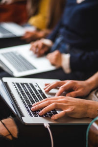 Midsection of colleagues using laptops in creative office