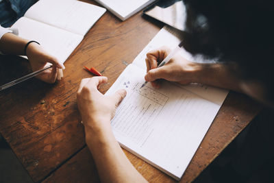 High angle view of teenage boy writing in book on table