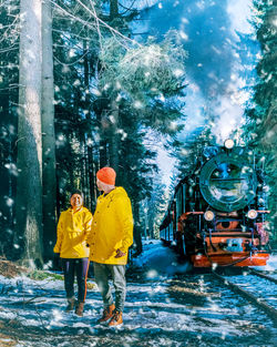 Rear view of people on road in forest during winter