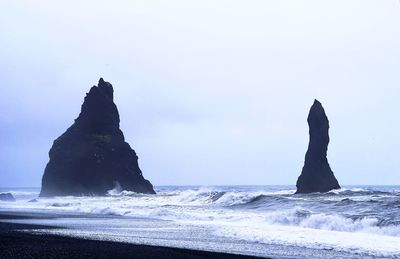 Rock formation on beach against clear sky