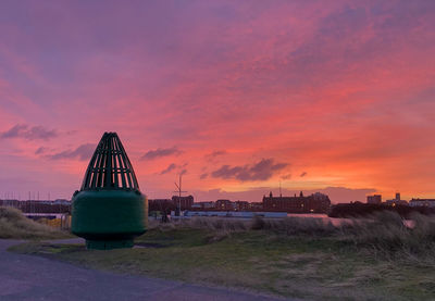 Buoy on land against romantic sky at sunset