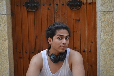 Portrait of man sitting against closed door