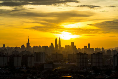 Petronas towers with cityscape against sky during sunset