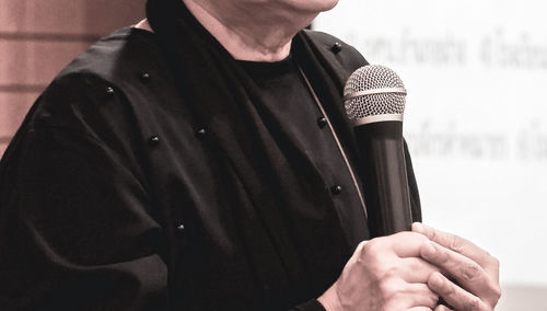 Midsection of man holding microphone in event