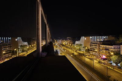 Illuminated street amidst buildings in city at night