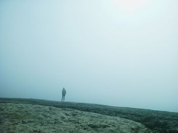 Man standing on rock during foggy weather