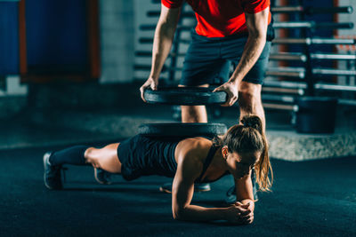 Instructor putting weights on woman exercising at gym