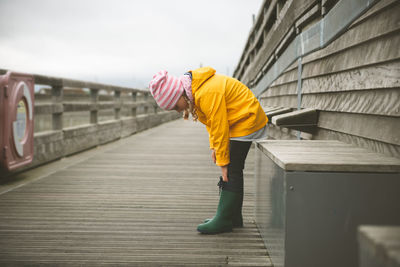 Side view of girl standing on pier against sky
