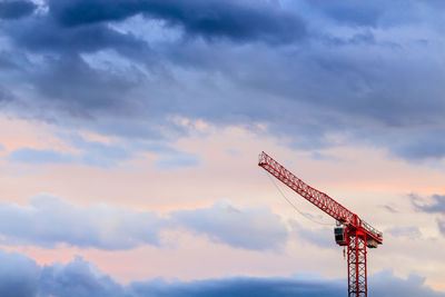 Low angle view of red crane against cloudy sky