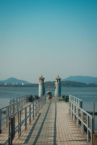 Pier over sea against clear blue sky