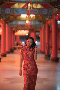 Full length of woman standing against red wall