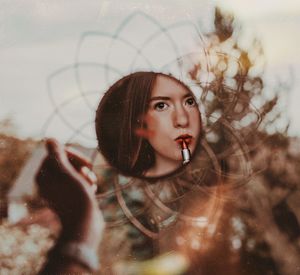 Close-up of woman applying lipstick reflecting on mirror against window