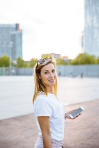 Portrait of smiling young woman standing on mobile phone