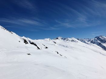 Scenic view of snow covered mountains against blue sky