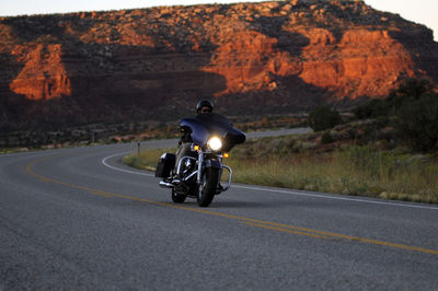 Rear view of man riding motorcycle on road