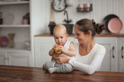 Portrait of cute boy sitting on bed at home