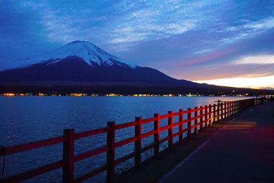 Scenic view of sea by mountains against sky during sunset