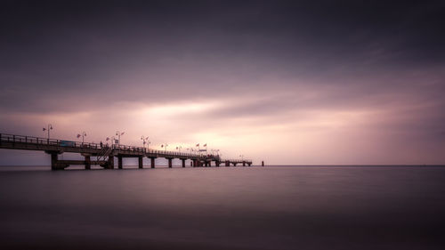 Pier over sea against sky during sunset