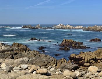 Rocky coastline of pacific grove, california with blue sky and slow shutter