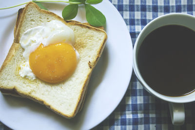 Fried egg on toast and black coffee in a glass.