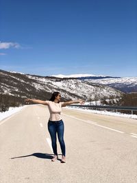 Full length of woman walking in the middle of a road against sky