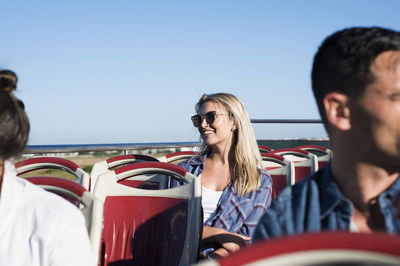 Tourists traveling in double-decker bus against clear blue sky