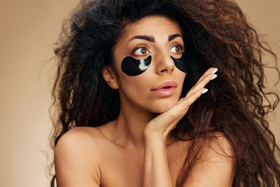 Portrait of young woman wearing sunglasses against wall