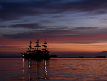 Silhouette sailboat in sea against sky during sunset