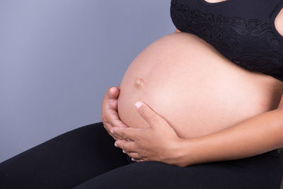 Midsection of pregnant woman with hands on stomach
