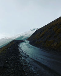 Scenic view of road by mountains against sky