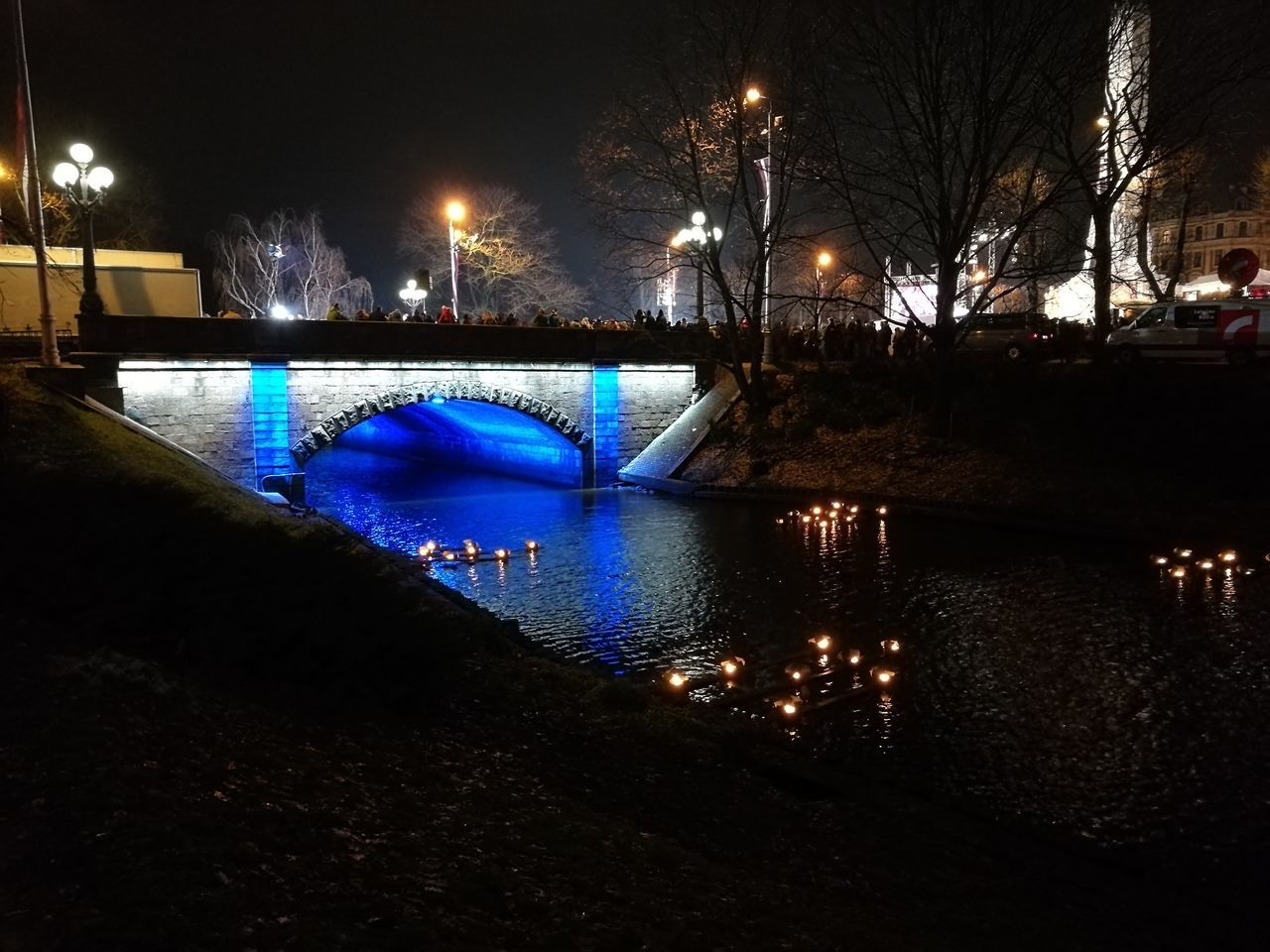 ILLUMINATED BRIDGE OVER WATER AT NIGHT