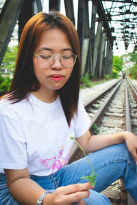 Mid adult woman sitting on railroad track