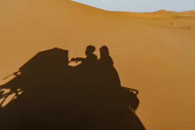 Silhouette people in desert against sky during sunset