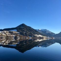 Scenic view of lake and mountains against clear blue sky