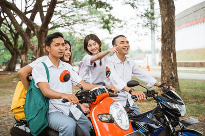 Portrait of smiling friends sitting on road