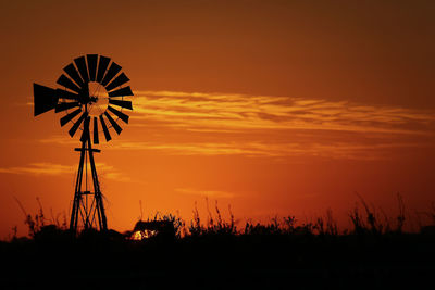 Wind turbines on landscape at sunset