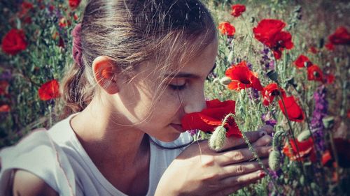 Close-up of girl smelling red flowers