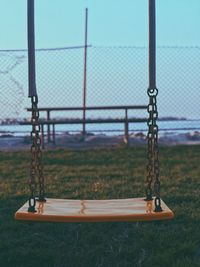 Empty swing on field against sky