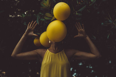 Woman with fruits over face on plants