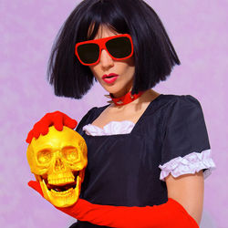 Demonic brunette vampire lady in red gloves holding gold skull. role-playing games, halloween, party